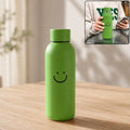 Green smiley-face travel water bottle with silicone sleeve and rounded cap