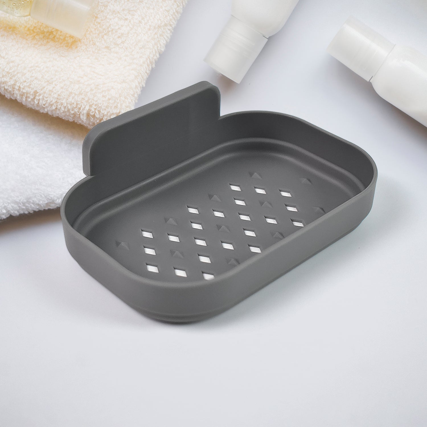 Wall-mounted dark gray soap dish with perforated drainage tray and raised back lip