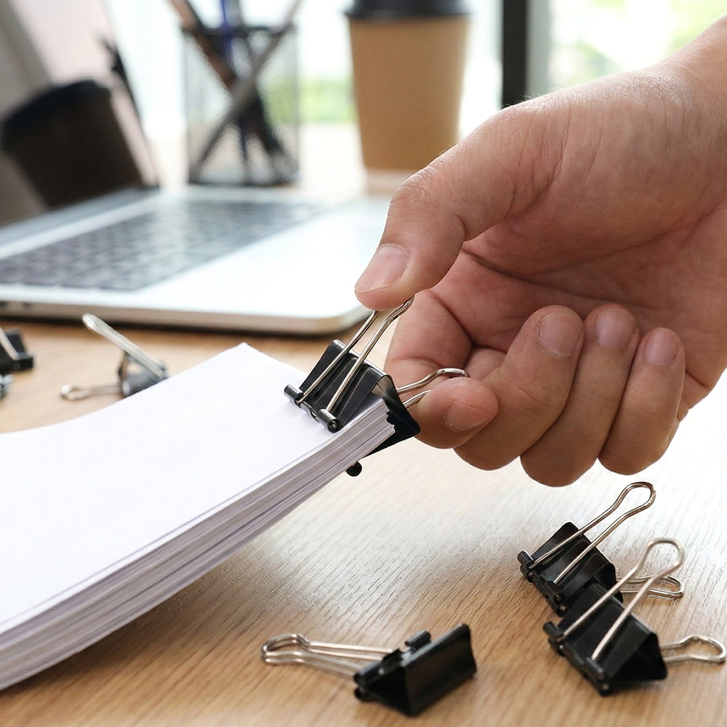 Black metal binder clips holding sheets of paper tightly