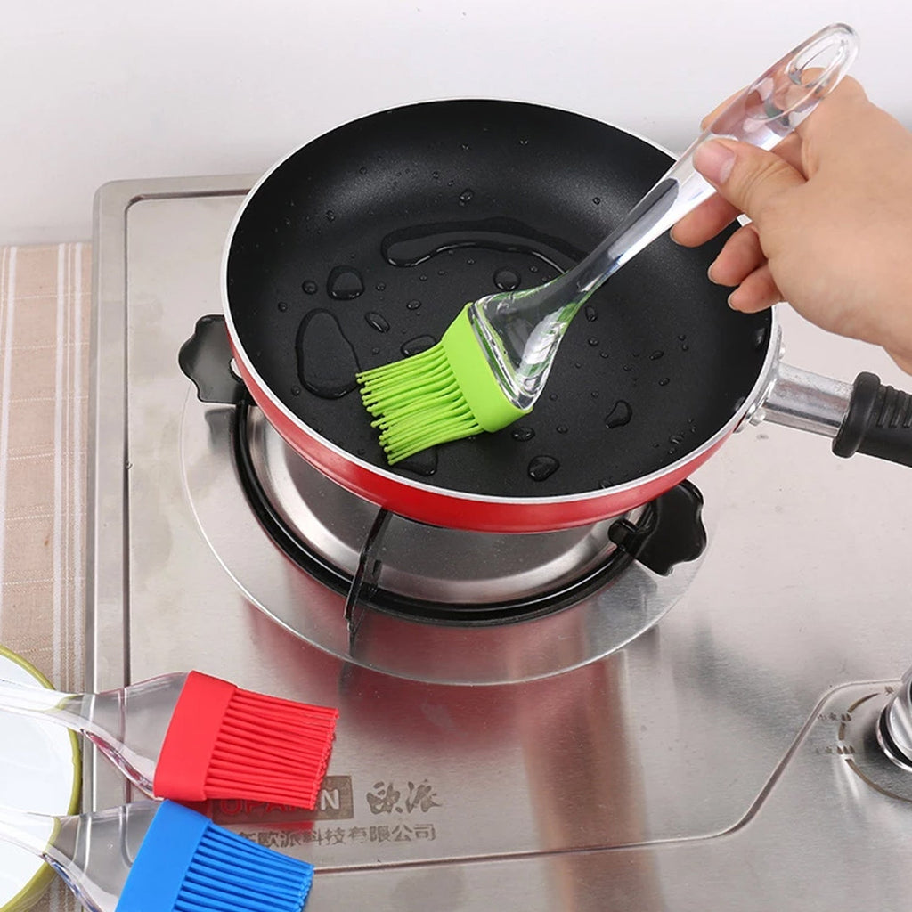 Silicone pastry brush with green bristles brushing a nonstick pot surface