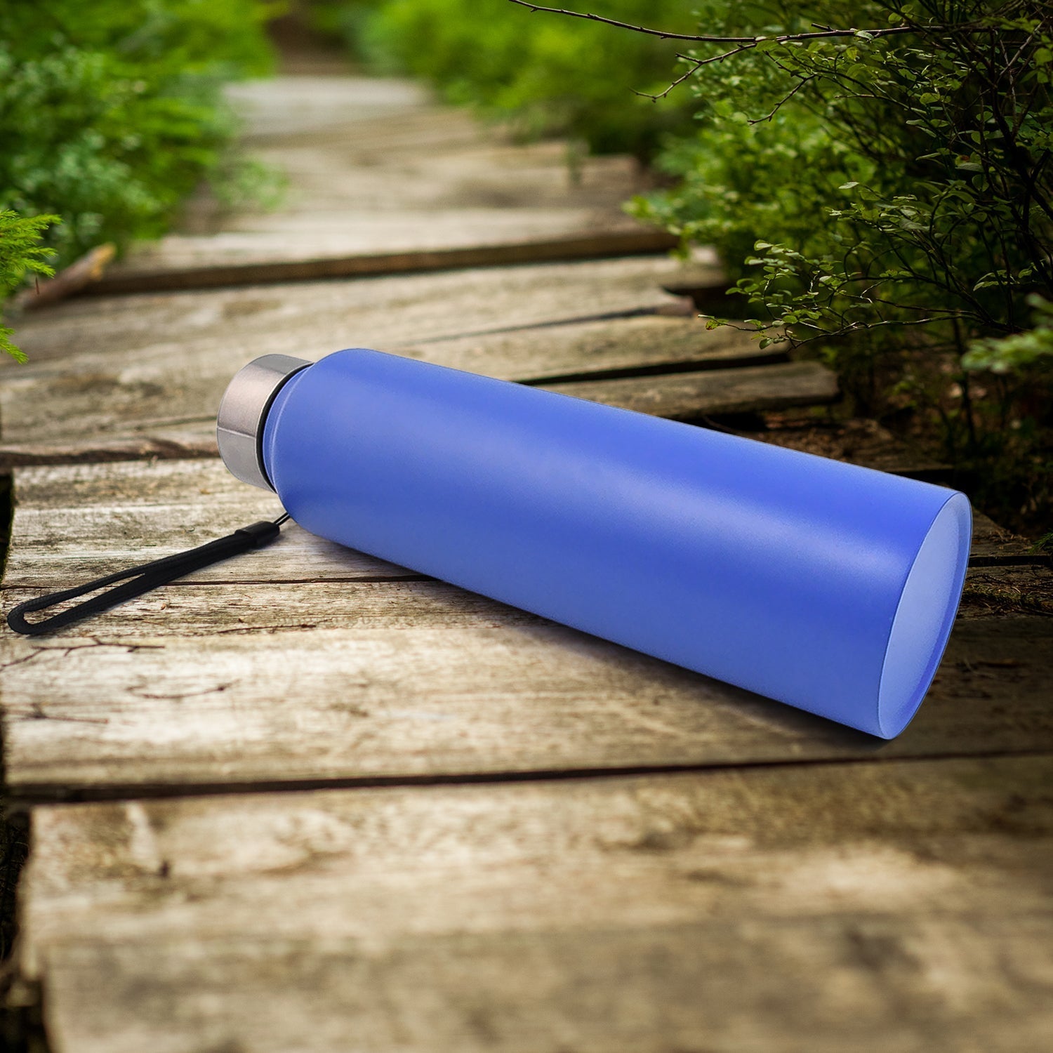Blue stainless steel water bottle lying on side with silver lid and wrist strap