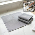 Gray microfiber cleaning towels, dual-sided weave; folded set on countertop surface