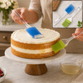Silicone pastry brush and spatula set, with blue brush and green-tined spatula, on cake