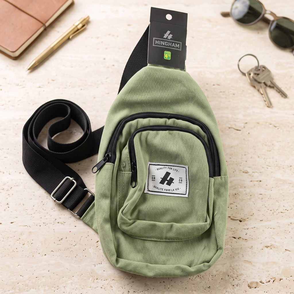 Green kids canvas sling crossbody bag on flat surface with adjustable strap