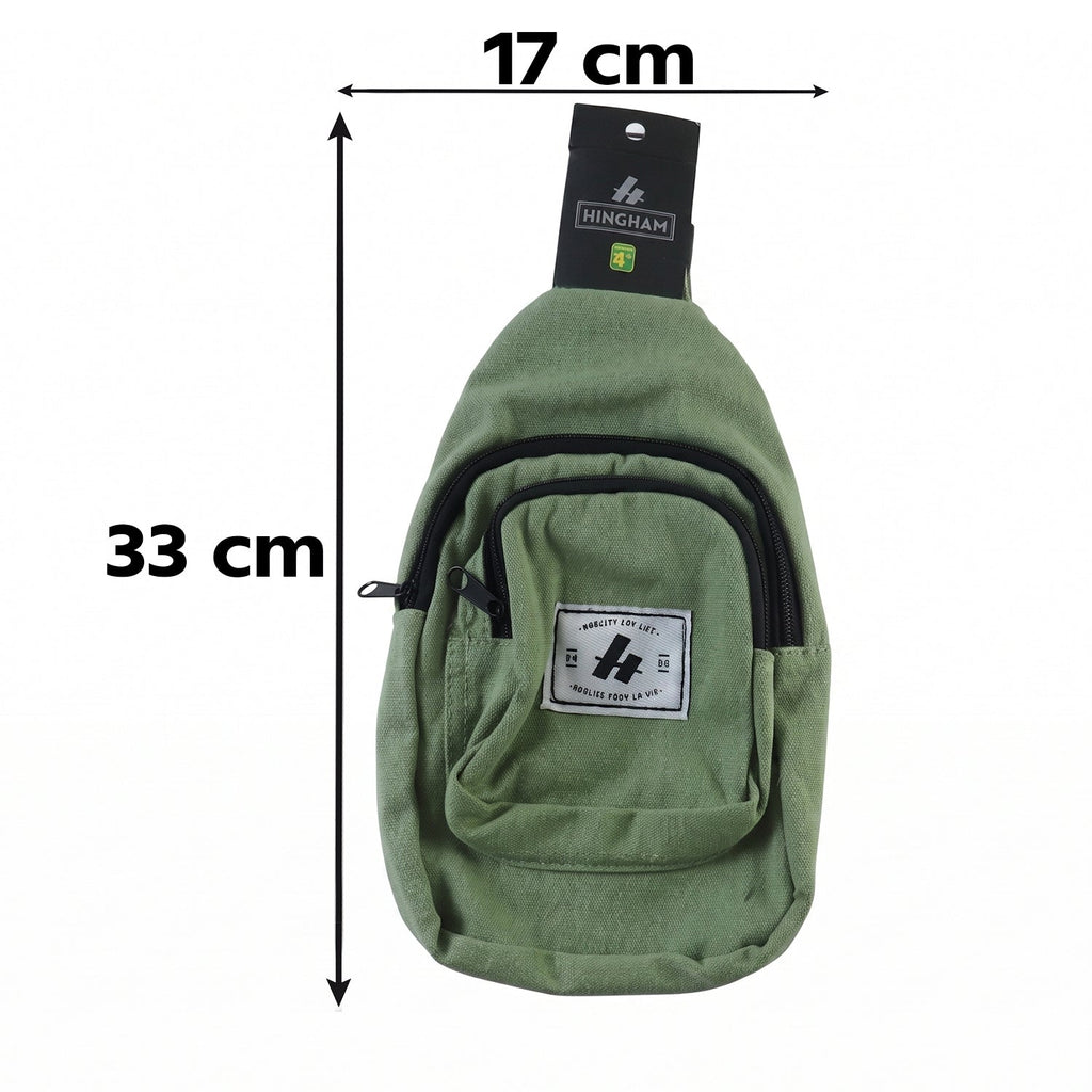 Green canvas sling crossbody bag front view with labeled patch and black zipper trim
