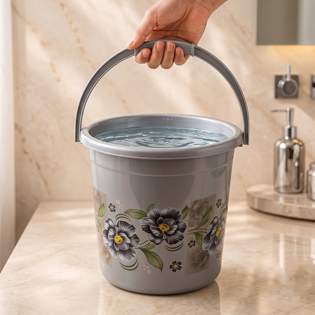 Gray plastic floral bathroom bucket with curved handle, held in a hand