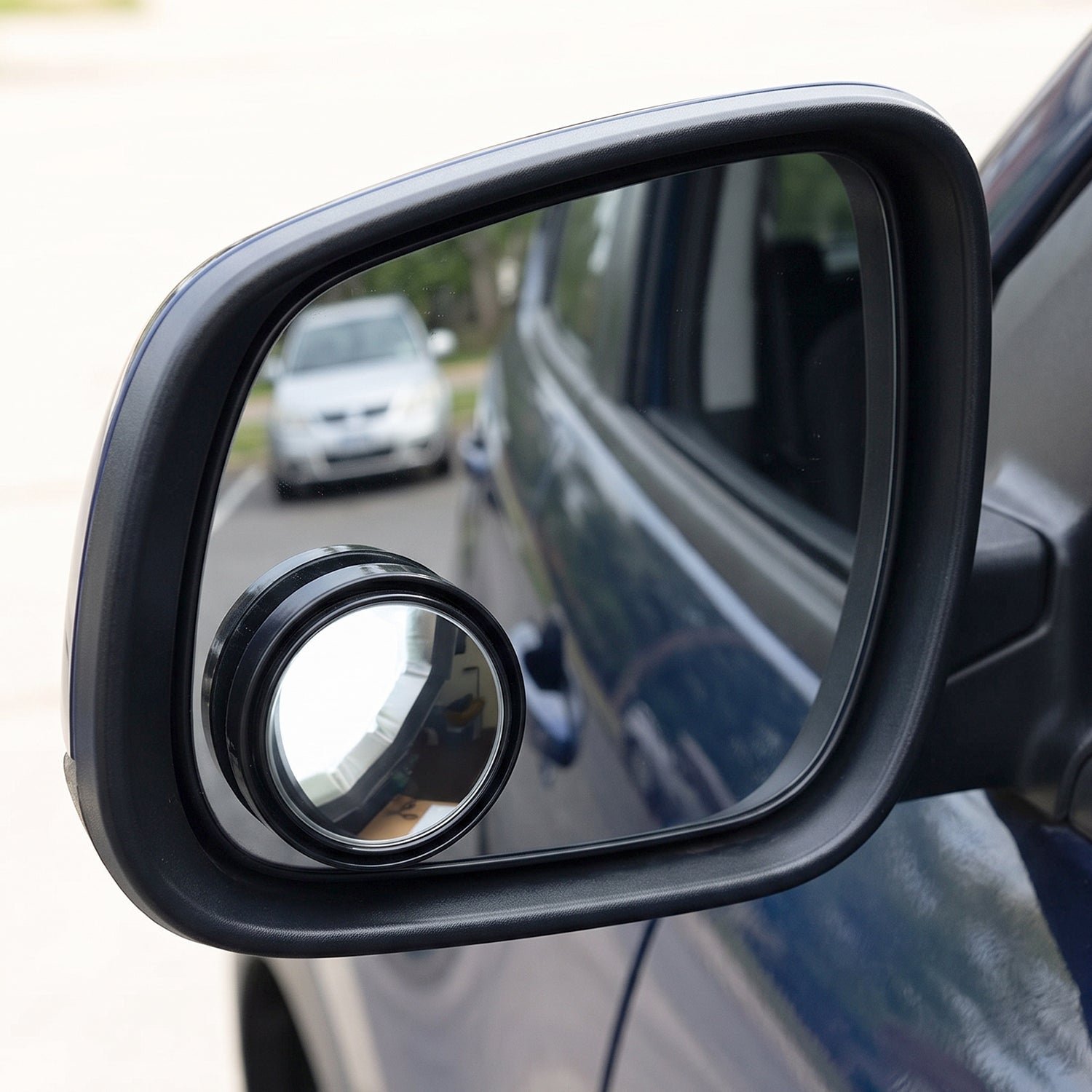 Round wide-angle blind spot mirror, black frame, mounted on car side panel