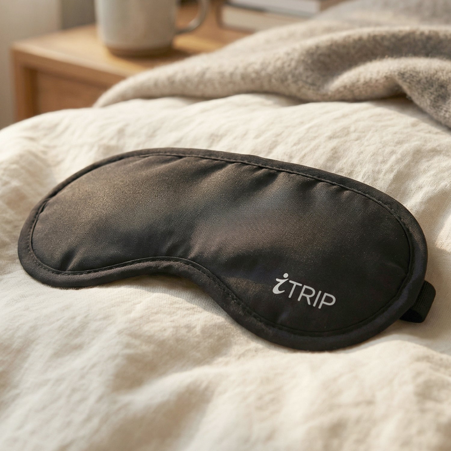 Black light-blocking sleep eye mask with centered logo on soft padded fabric