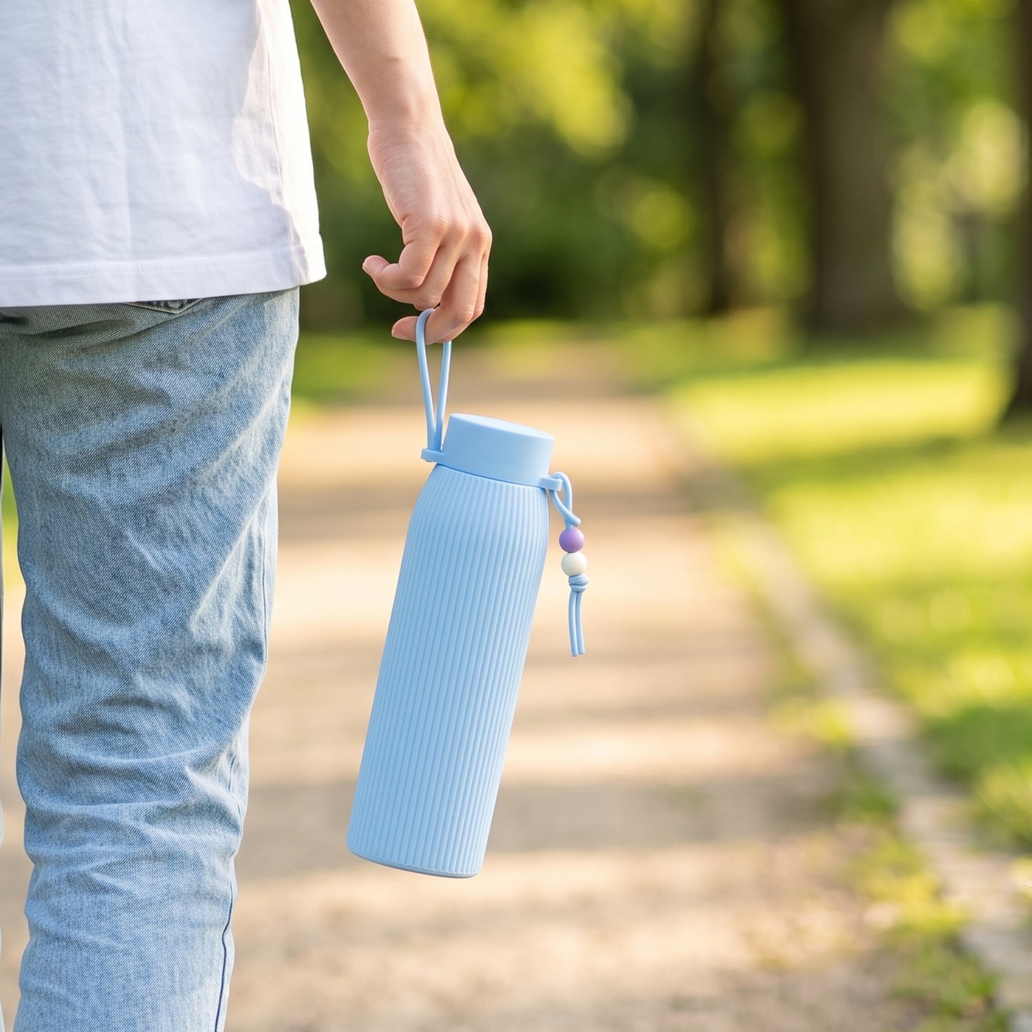 Light blue ribbed glass water bottle with silicone lid and hanging carry cord