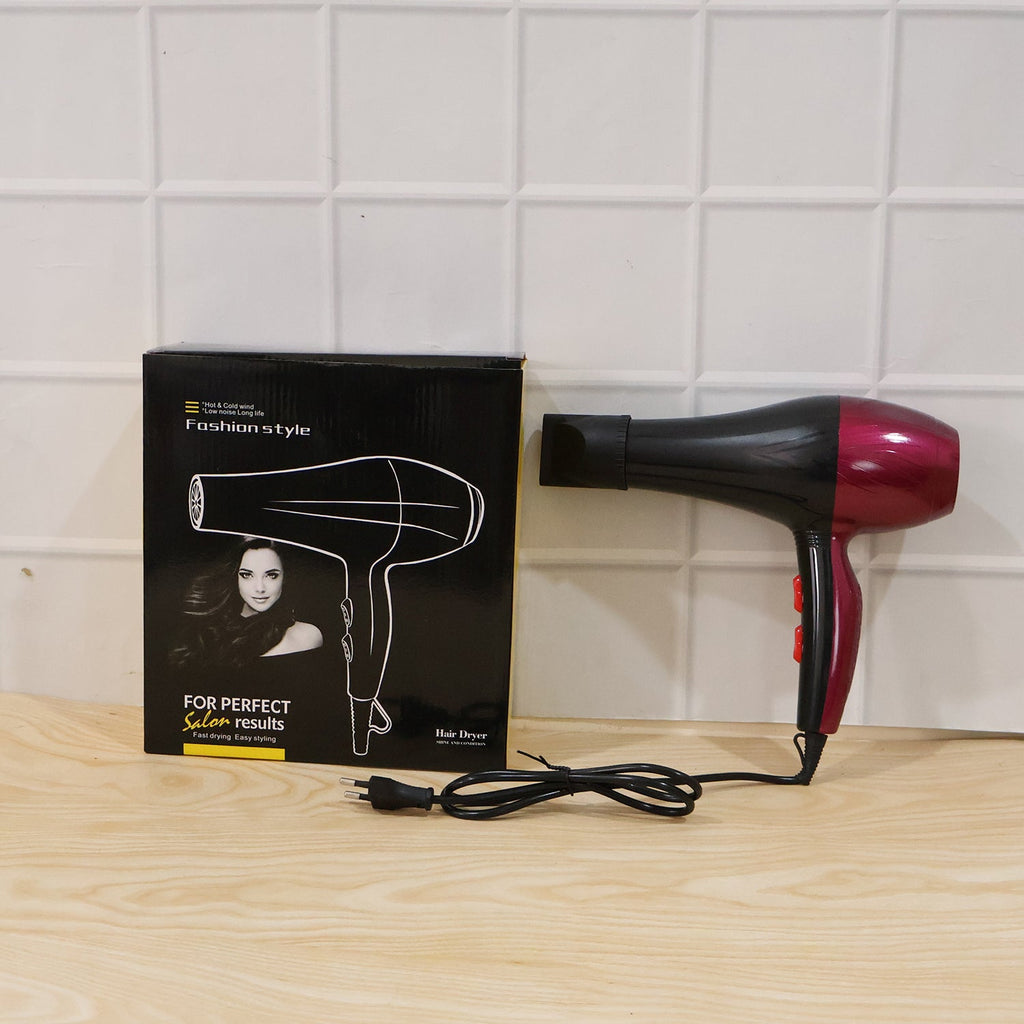 Black and burgundy hair dryer with box and power cord on wood surface