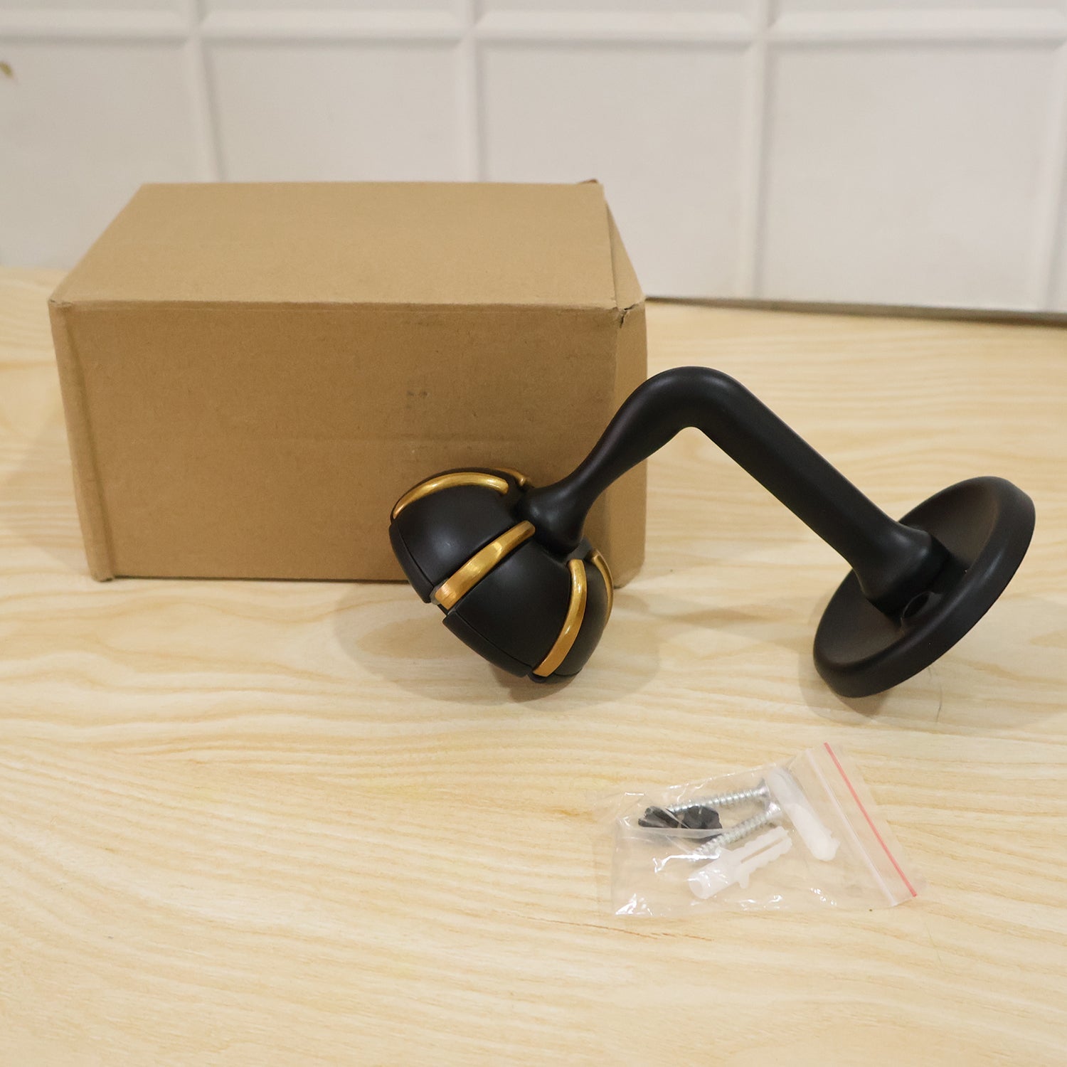 Black wall hook with gold trim, with included mounting screws and parts