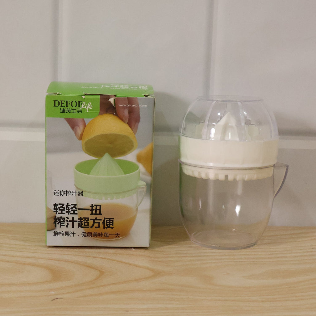 Plastic mini citrus squeezer with clear cup and white press top, shown with box