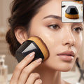 Foundation makeup brush with golden bristles and black hex handle, sweeping on face