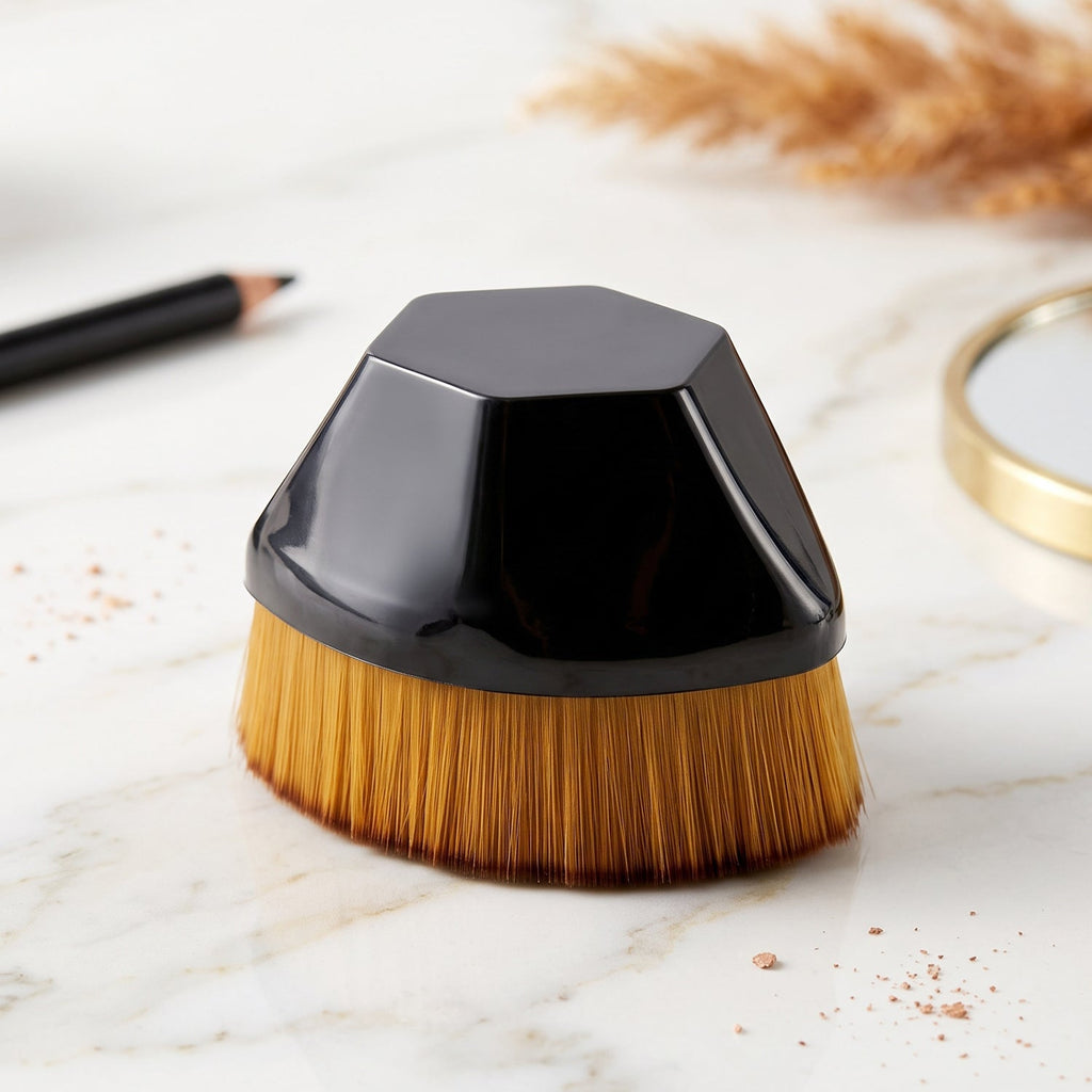 Foundation makeup brush with golden bristles and black dome base on marble surface