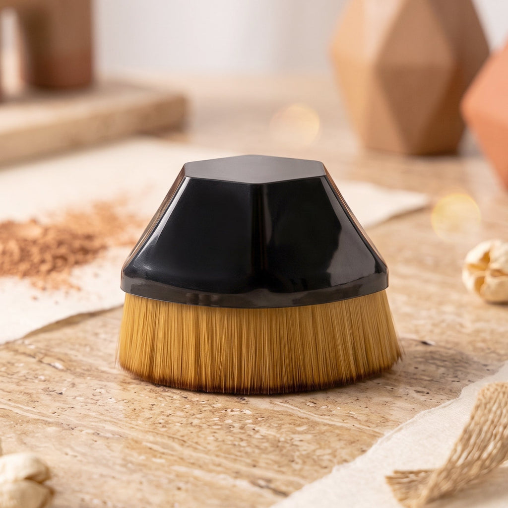 Foundation makeup brush with golden bristles and black dome base on wooden counter