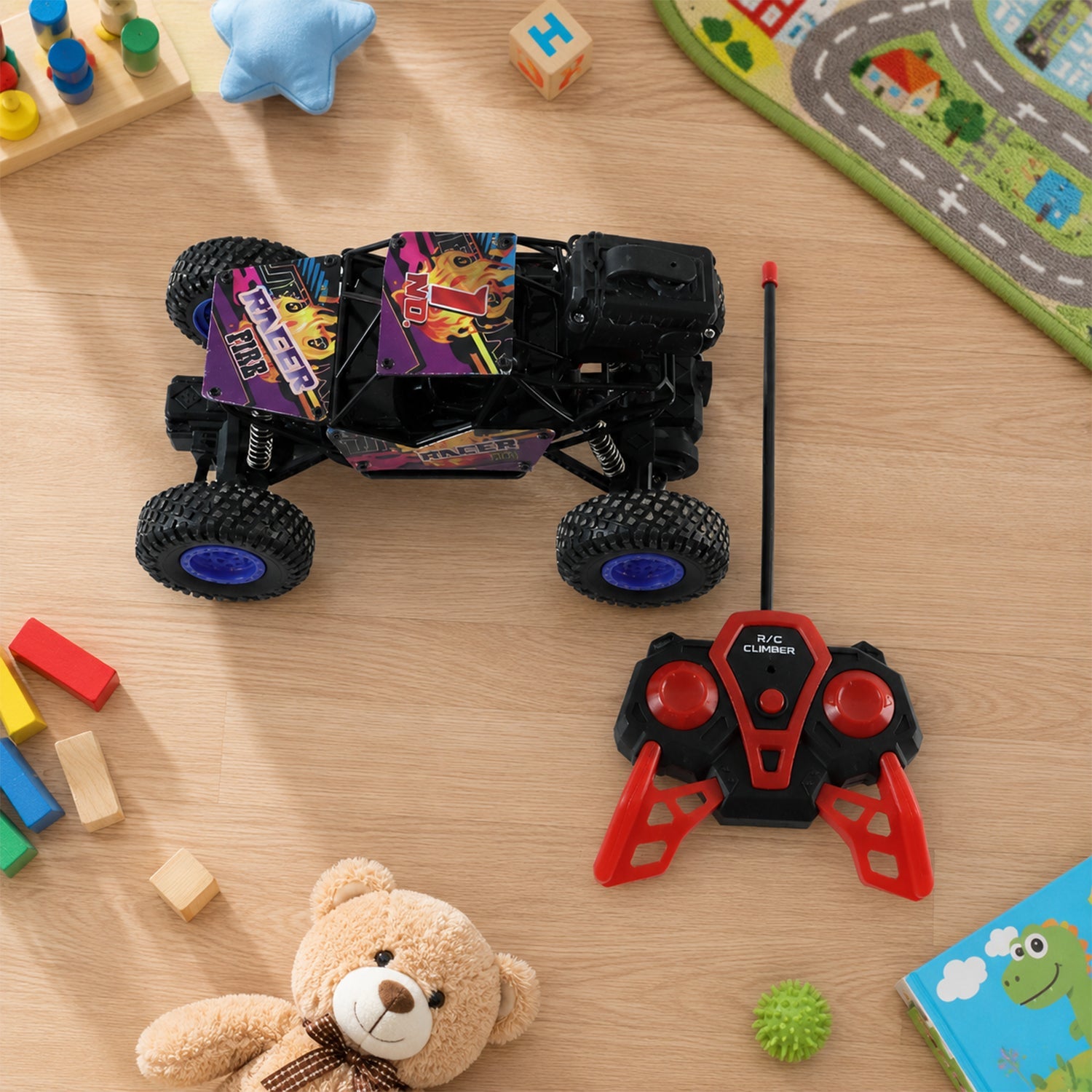 Rock crawler toy truck with purple graphics and blue tires, with red controller on tabletop.