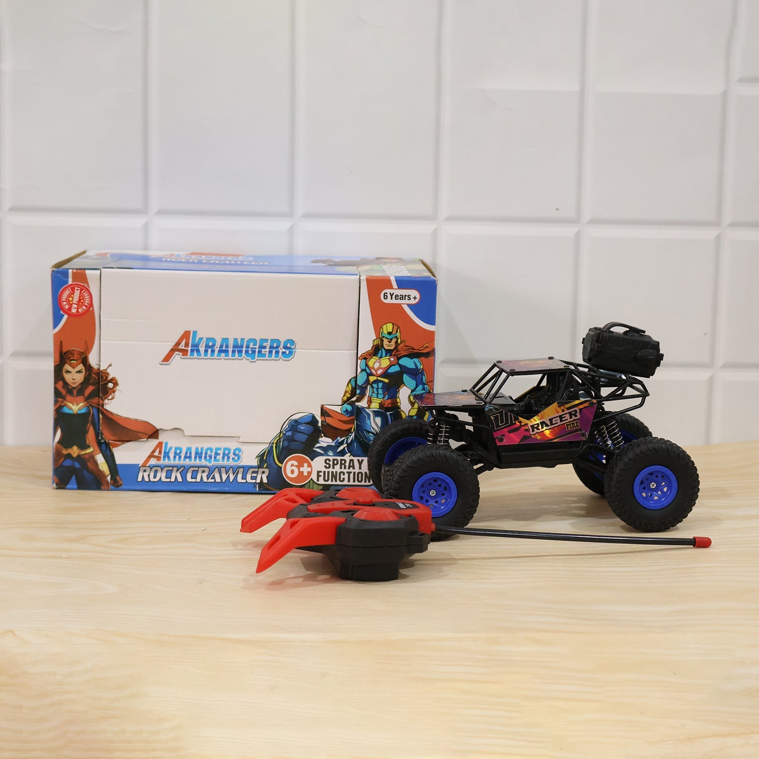 Boxed rock crawler toy set with black-and-pink truck, blue wheels, and red remote parts.