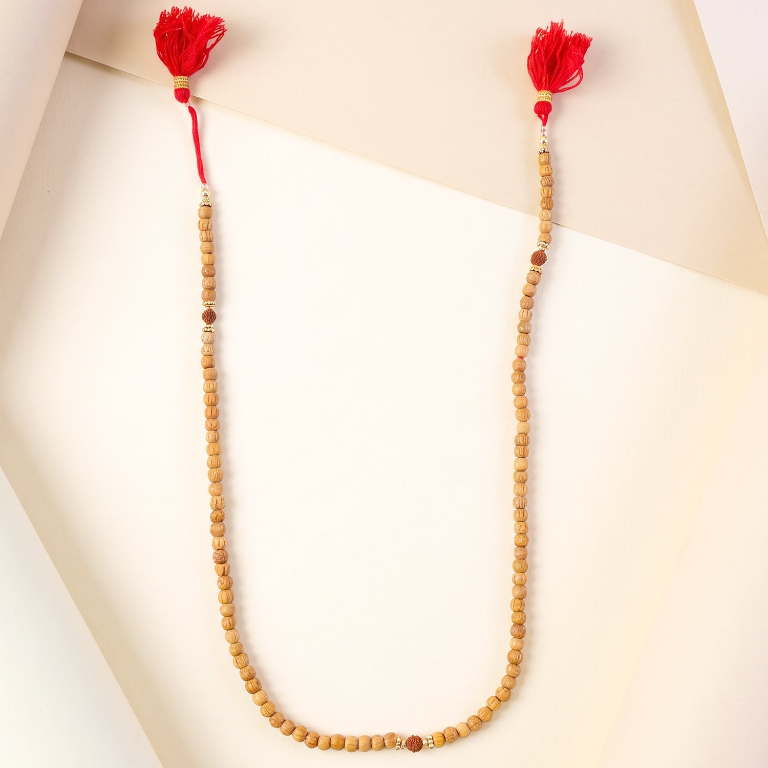 Sandalwood japa mala with light wood beads and bright red tassels on both ends