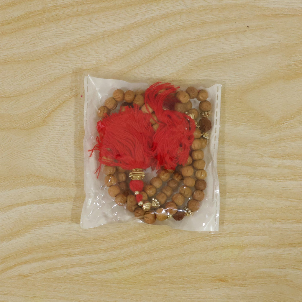 Sandalwood mala beads and red tassel bundle in clear plastic bag