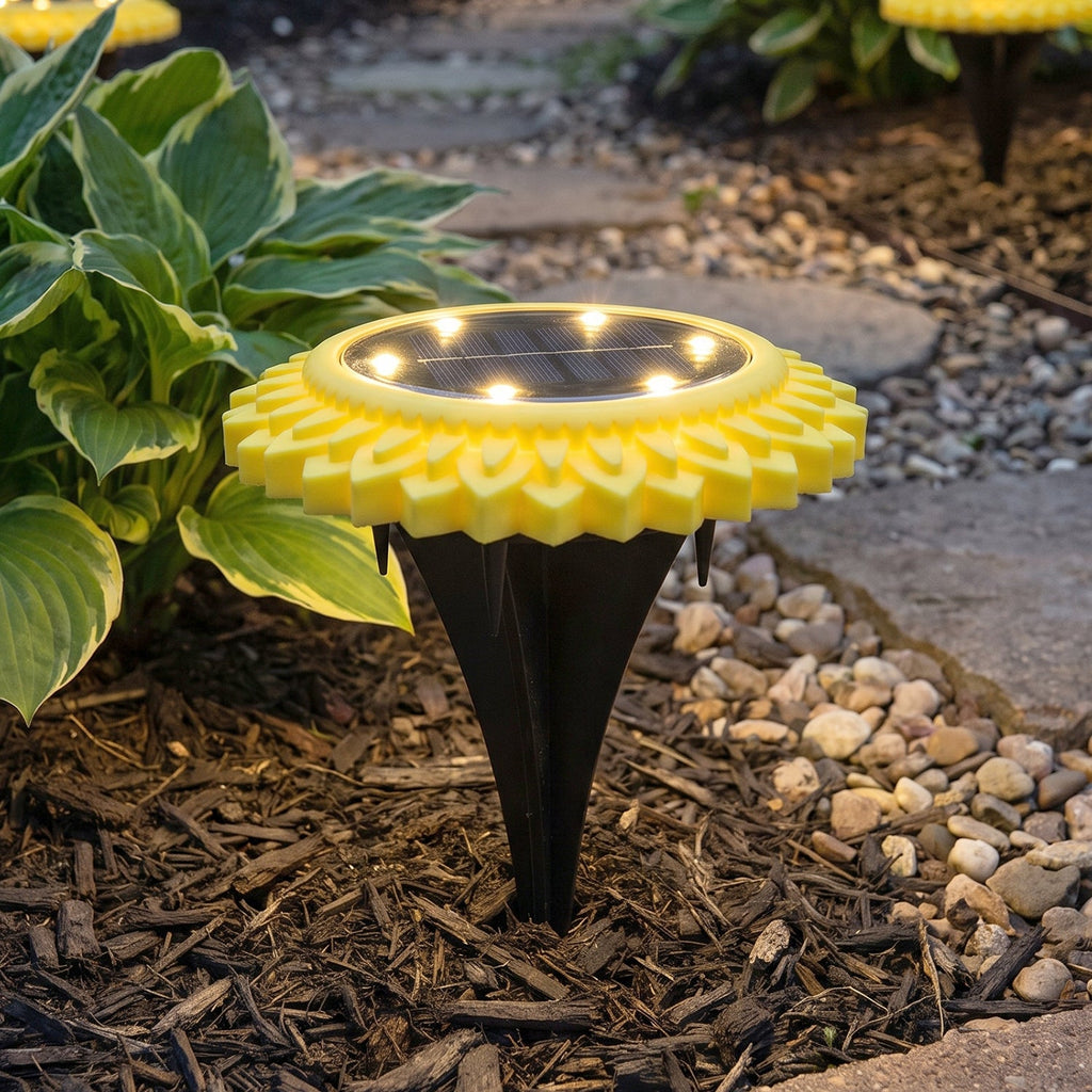 Close-up sunflower solar path light with warm glowing LED disc on a black stake