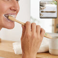 Bamboo toothbrush with soft bristles, held at an angle during brushing
