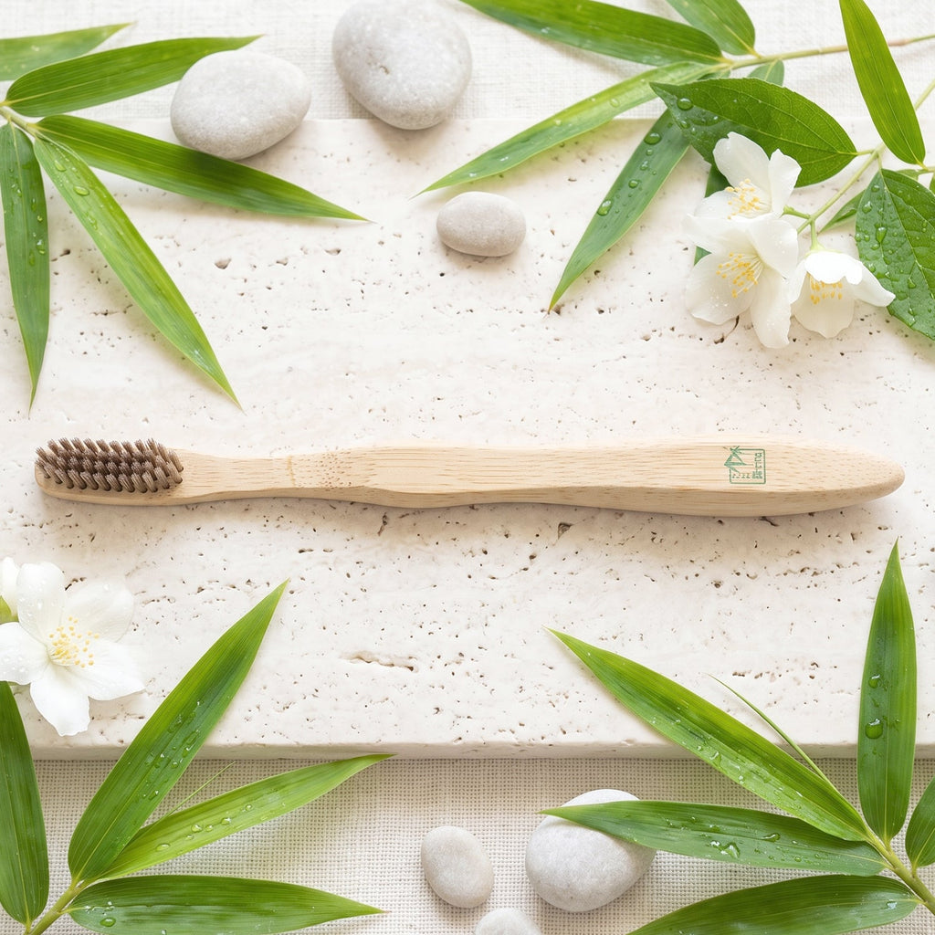 Soft bristle bamboo toothbrush on textured surface, bristle head facing left