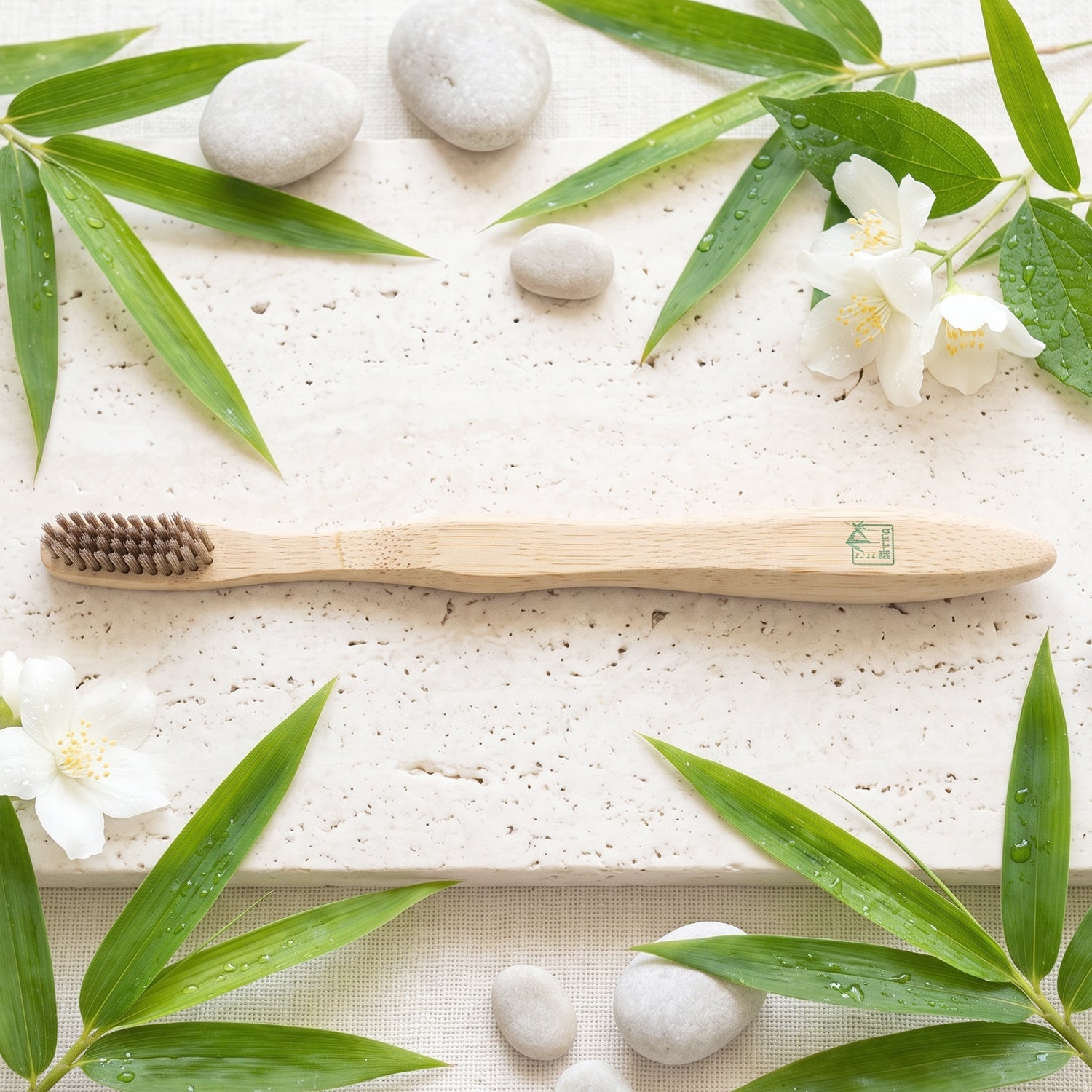 Soft bristle bamboo toothbrush on textured surface, bristle head facing left