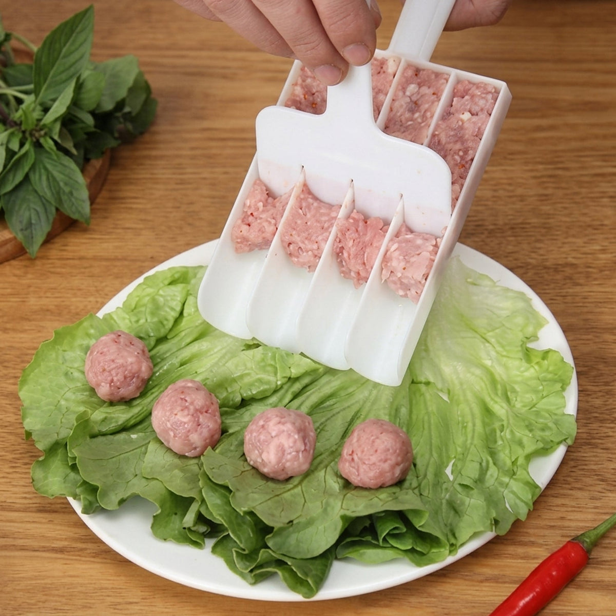 Fritter maker scoop dispensing from white multi-cavity tray onto lettuce with balls (XcelCraft)