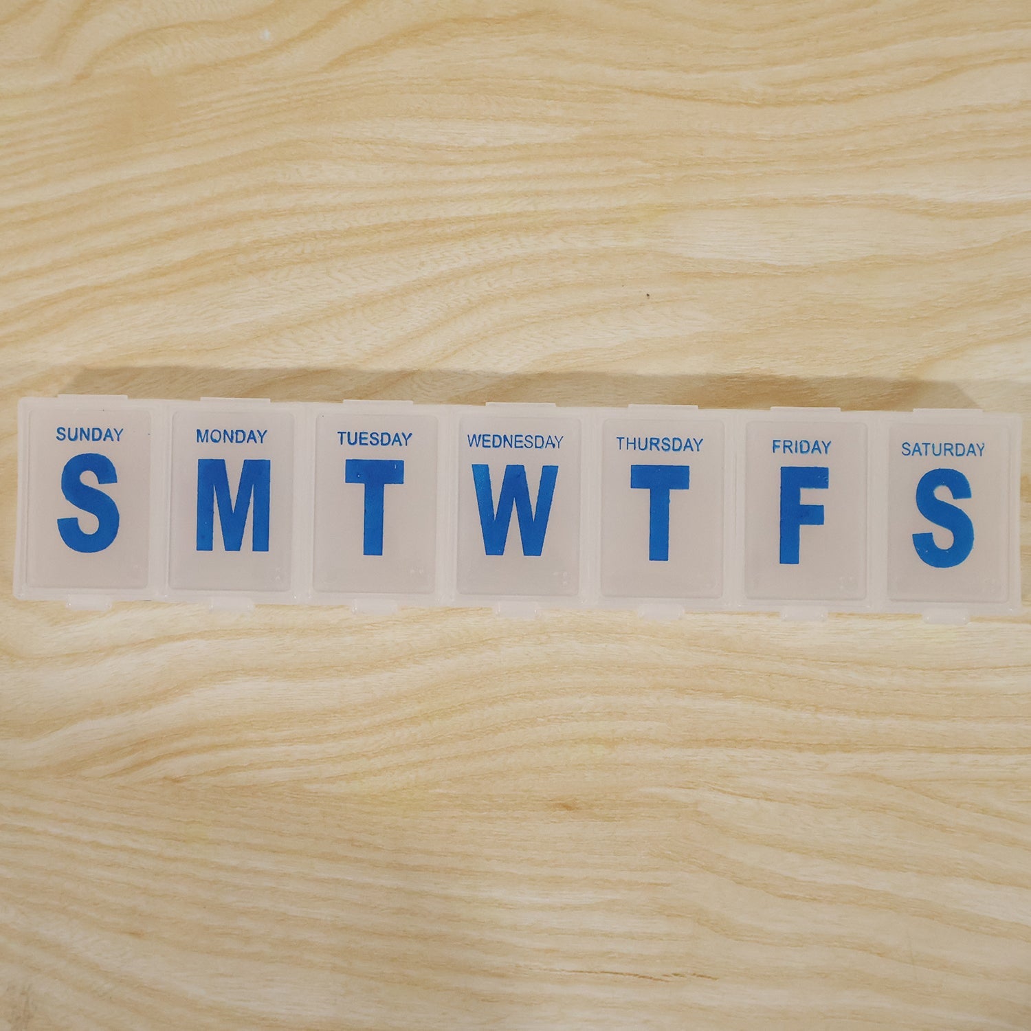 Close-up of 7-day pill organizer lid with blue Sunday to Saturday labels