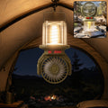 Portable solar camping fan and LED lantern, hanging with lit glass top and front fan grille