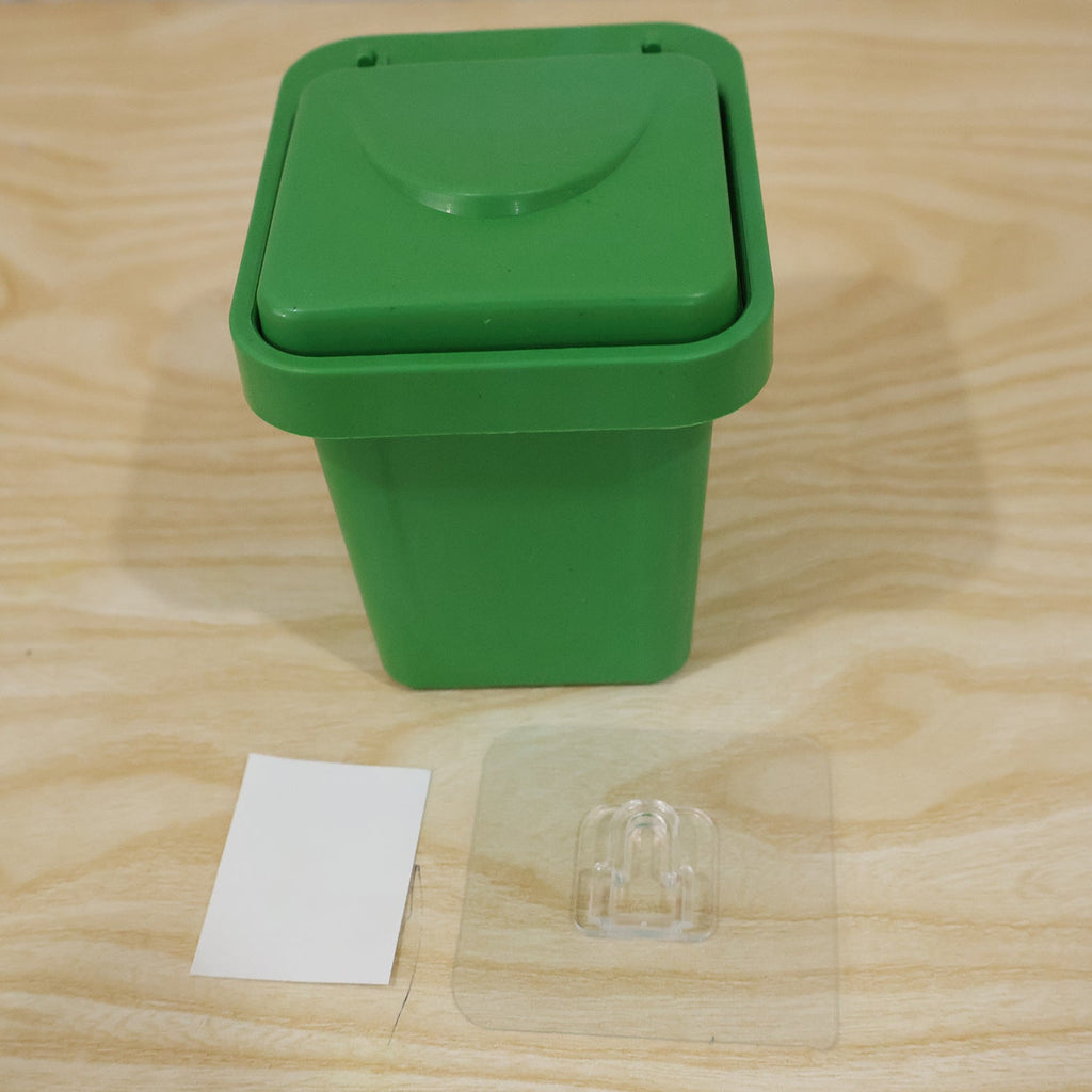 Green mini dustbin ashtray with closed flip lid and clear inner cover on wood surface
