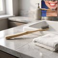 Bamboo toothbrush with soft gray bristles and wooden handle, angled view