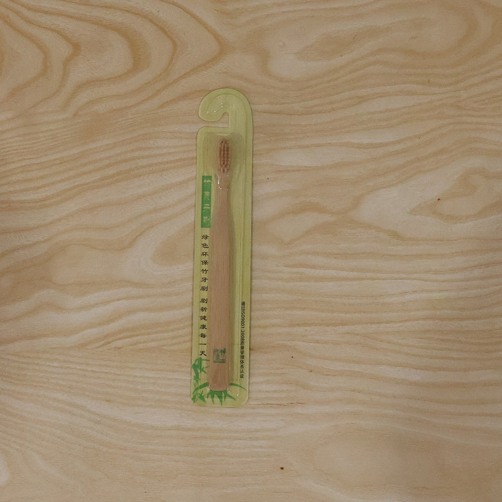 Bamboo toothbrush in sealed packaging on a light wood background