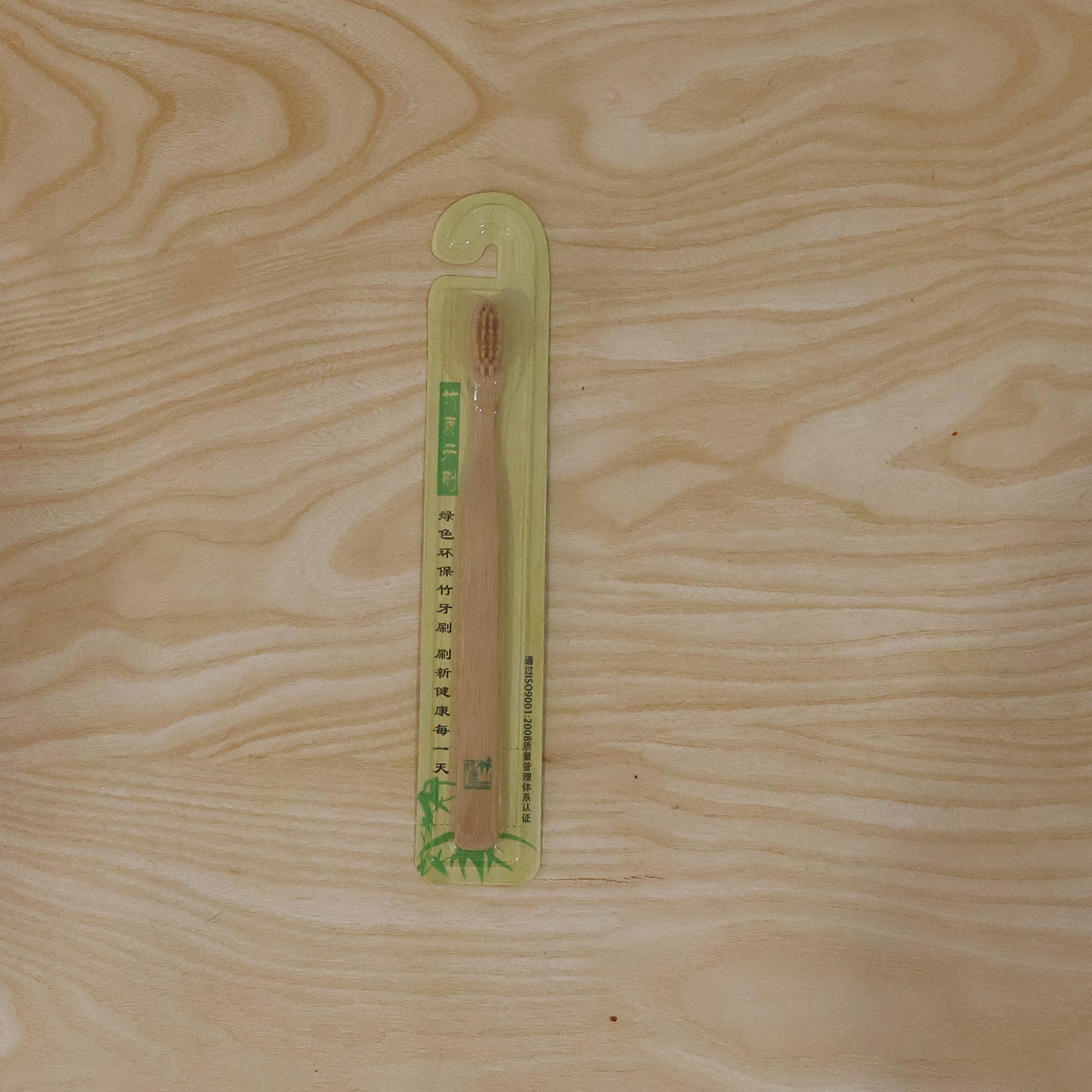 Bamboo toothbrush in sealed packaging on a light wood background