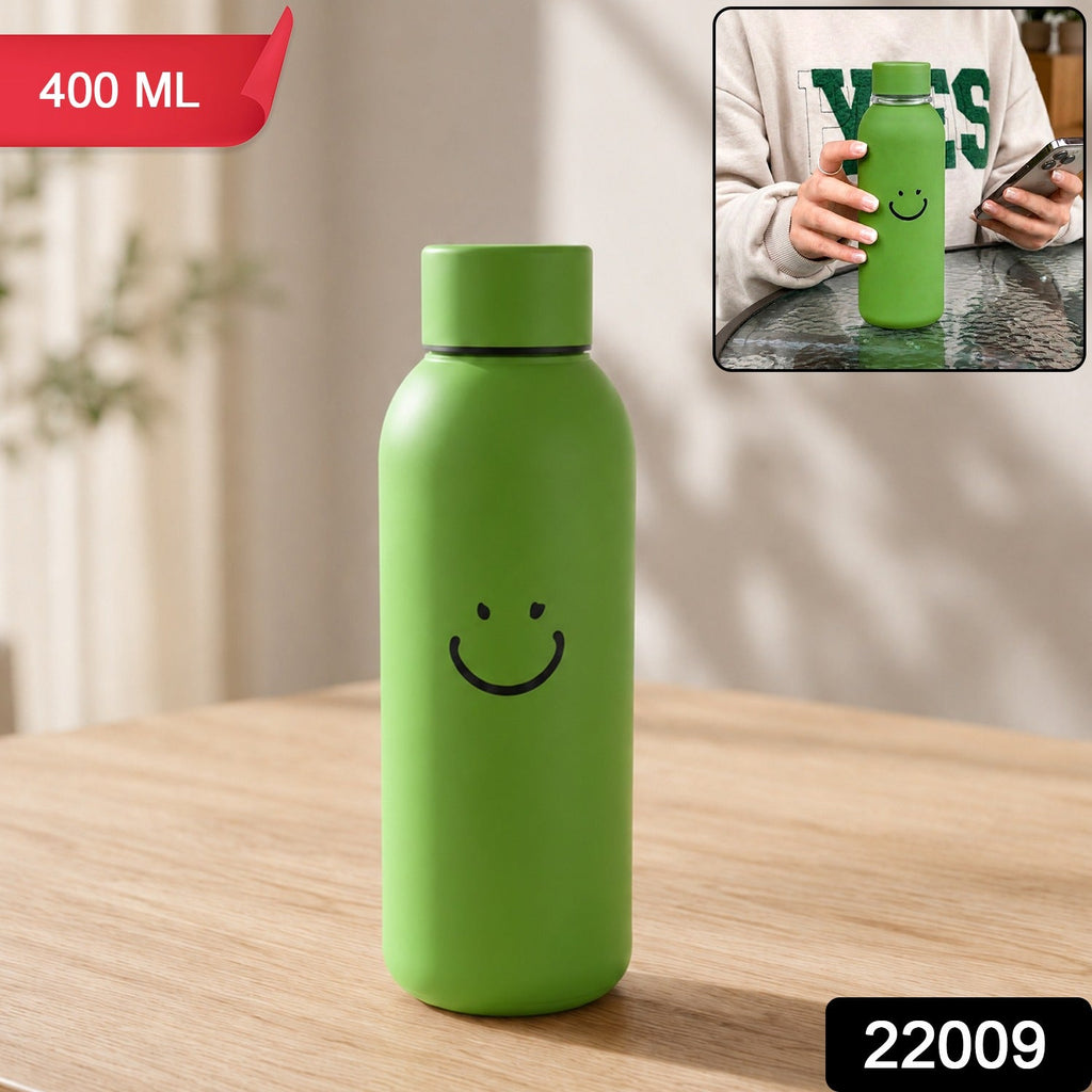 Green smiley-face travel water bottle with silicone sleeve, upright on tabletop