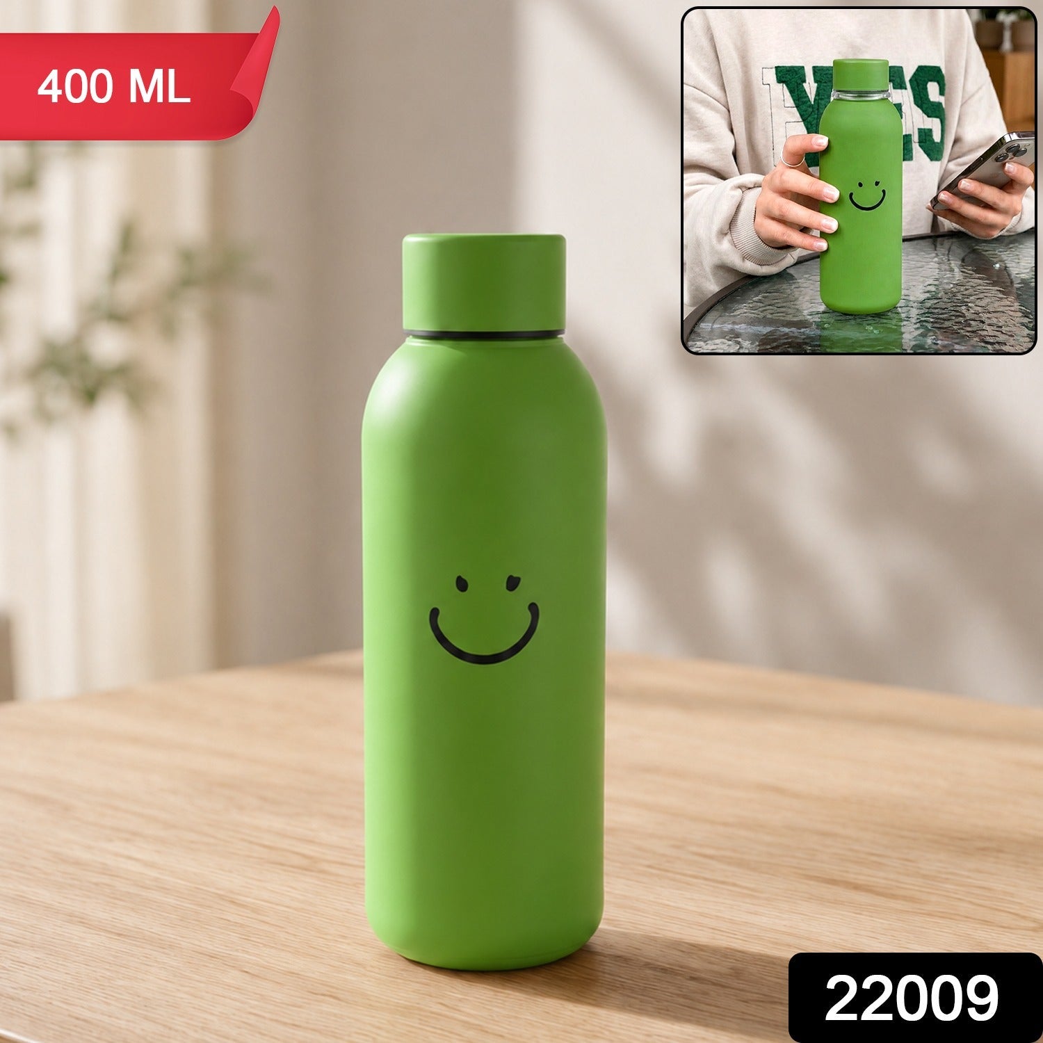 Green smiley-face travel water bottle with silicone sleeve, upright on tabletop