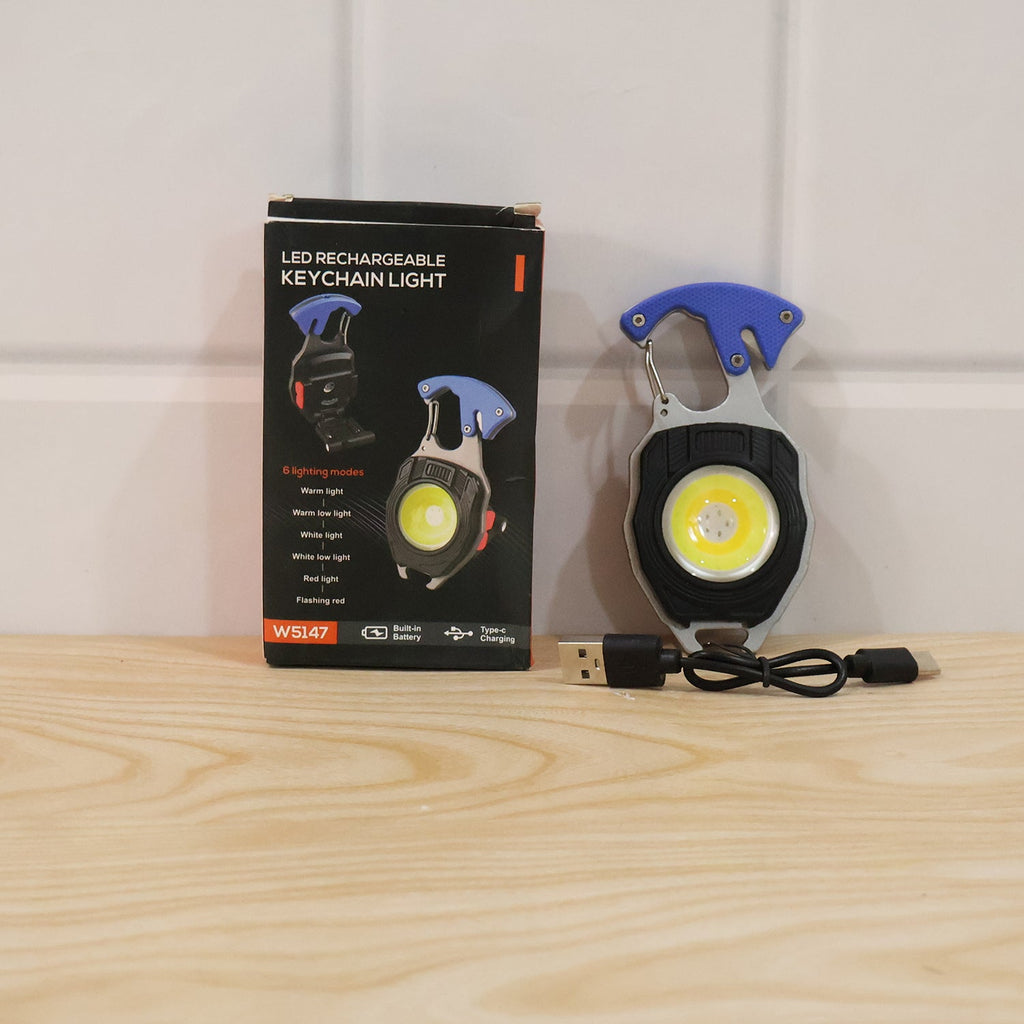 Keychain mini flashlight and charging cable in retail box, placed on wooden surface