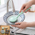 Kitchen sink scrubber with mint handle and stainless steel bristle pad, rinsed under running water