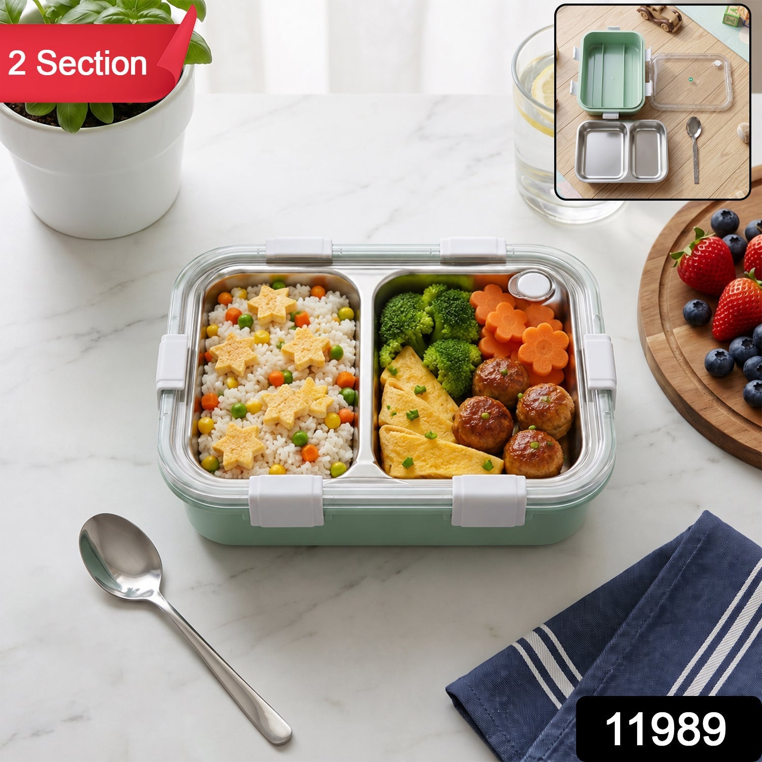 Two-compartment stainless lunch box with transparent lid, mint base, spoon on table